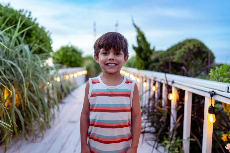 a little boy smiling for a picture on a deck