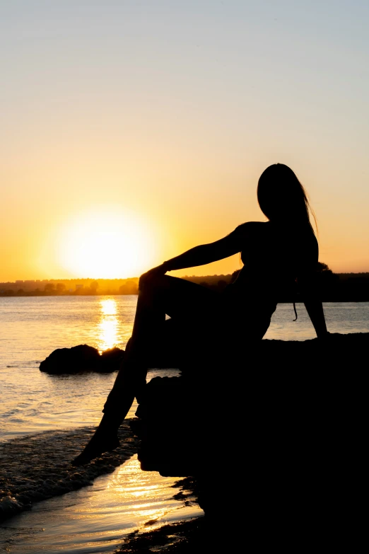 a person sitting on a rock at the beach