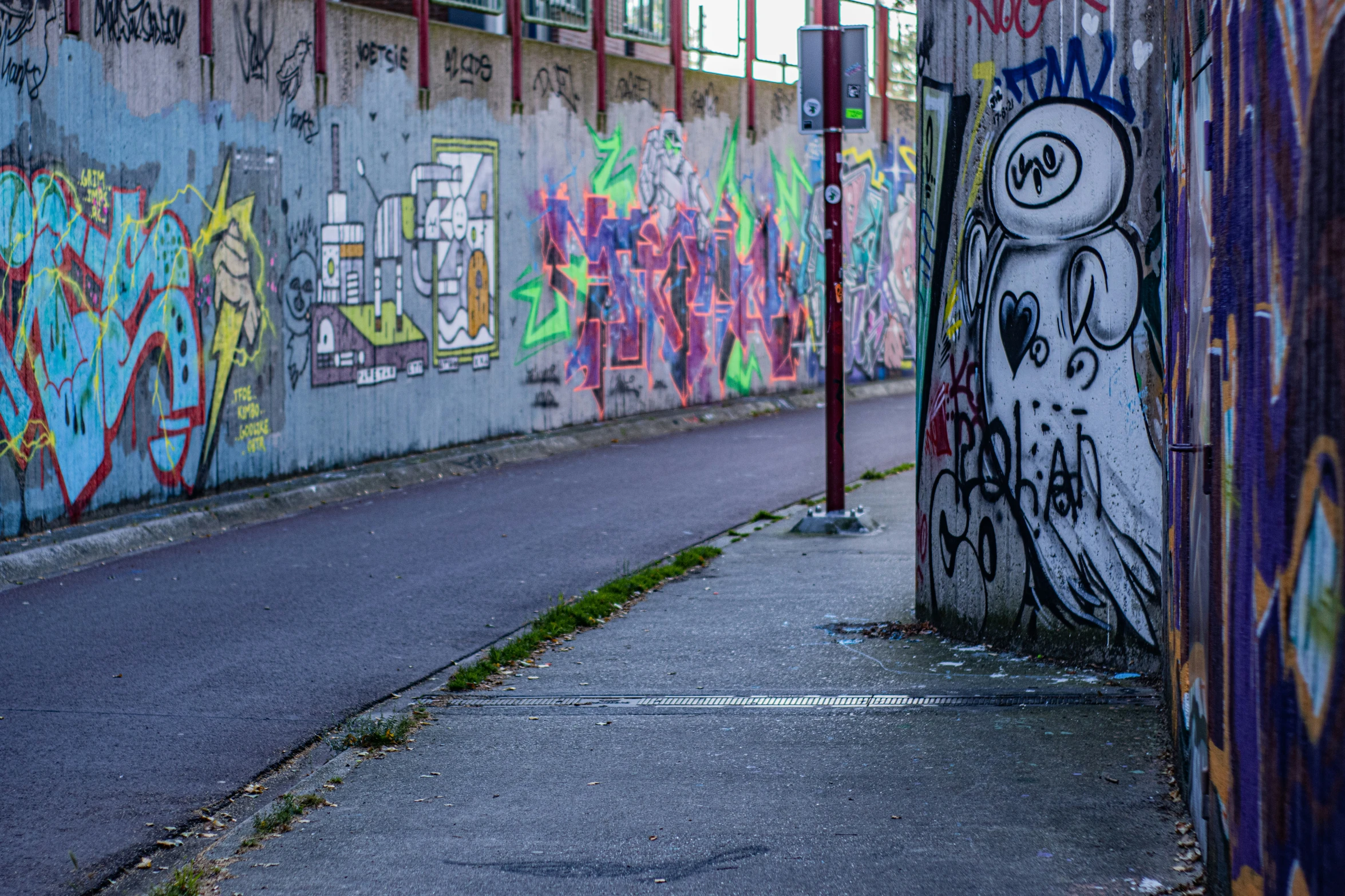 a long wall covered in graffiti with a street corner