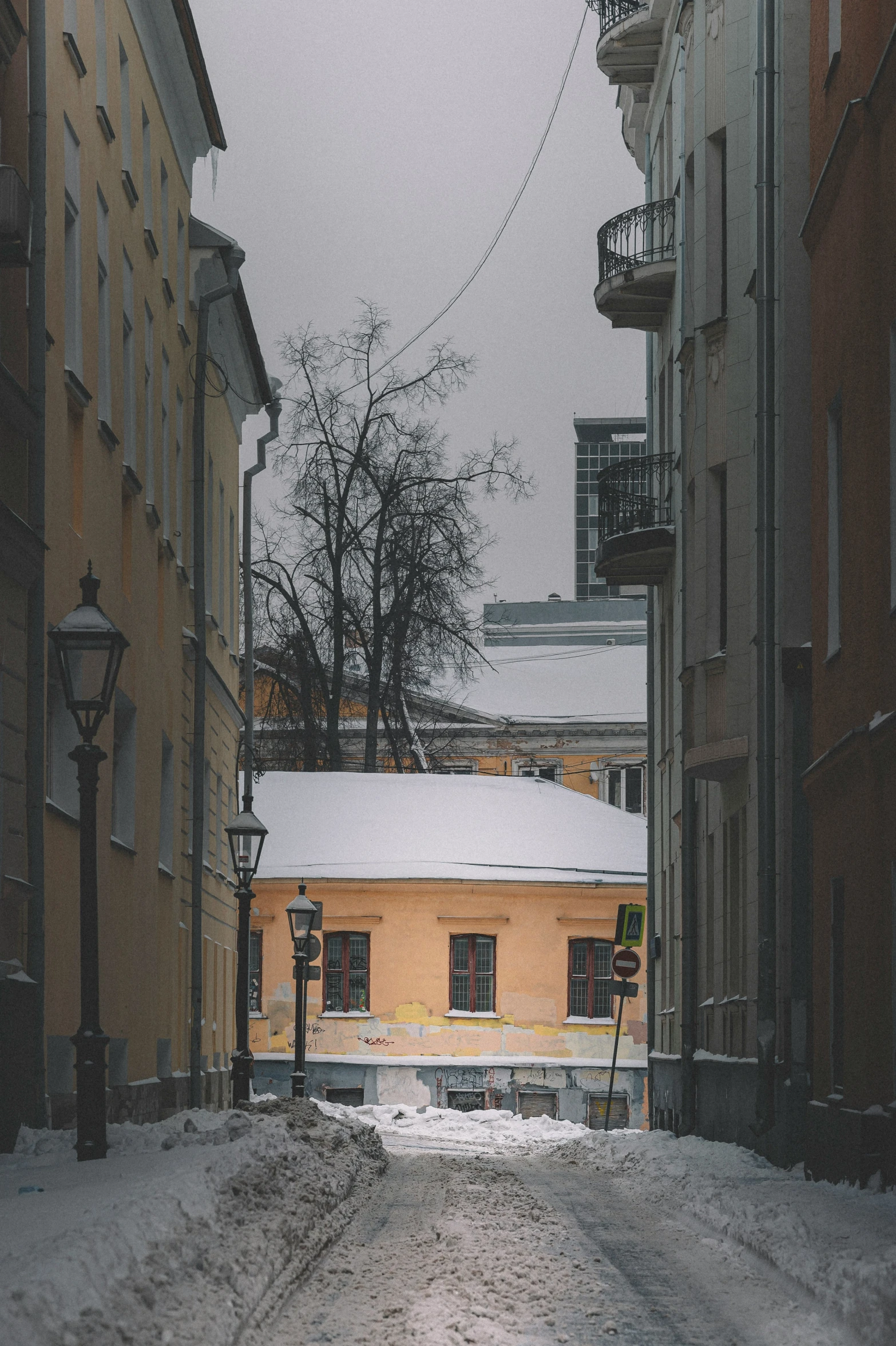 a snowy street is surrounded by small brick buildings