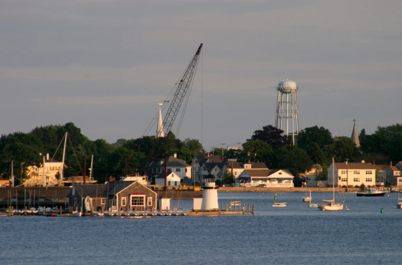 a boat traveling on the water past houses and an old water tower