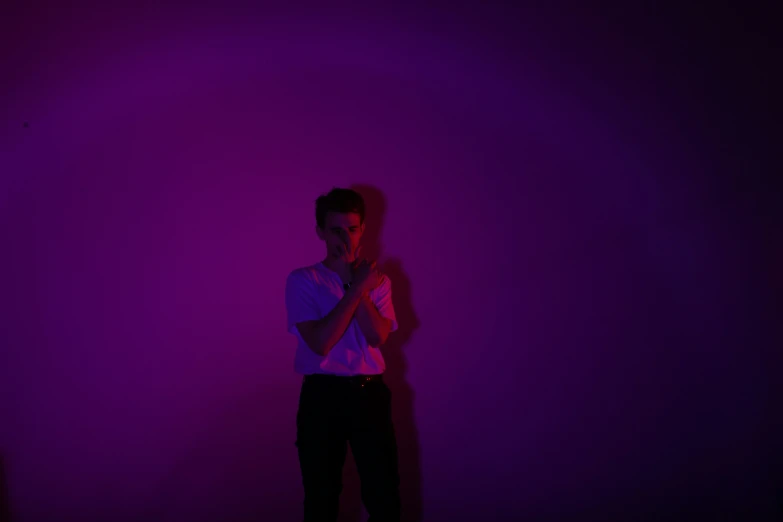 a man standing with his hands folded up in a dimly lit room