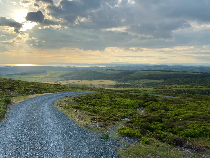 an empty winding country road with green trees and rolling hills