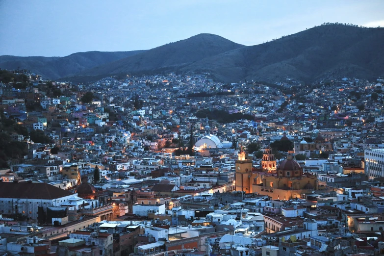 a city with mountain in background that has lights on at night