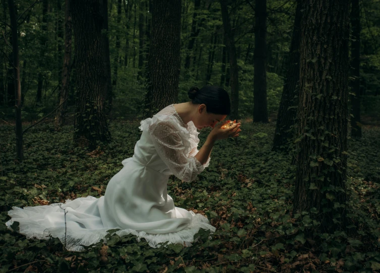 a woman in a white dress is holding pizza in the woods