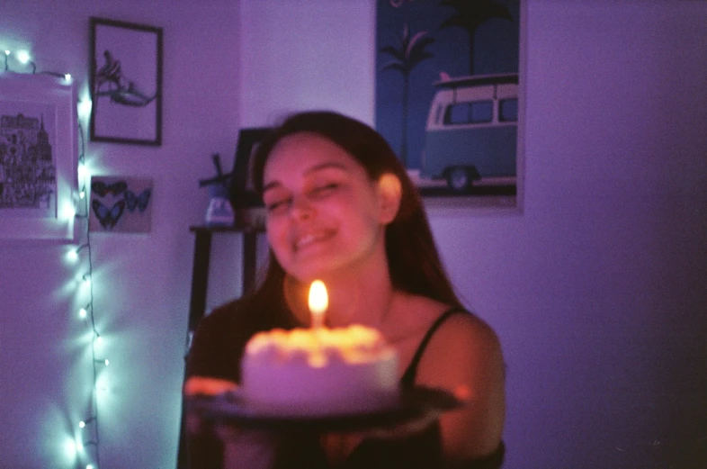 the woman is holding a cake with lit candles