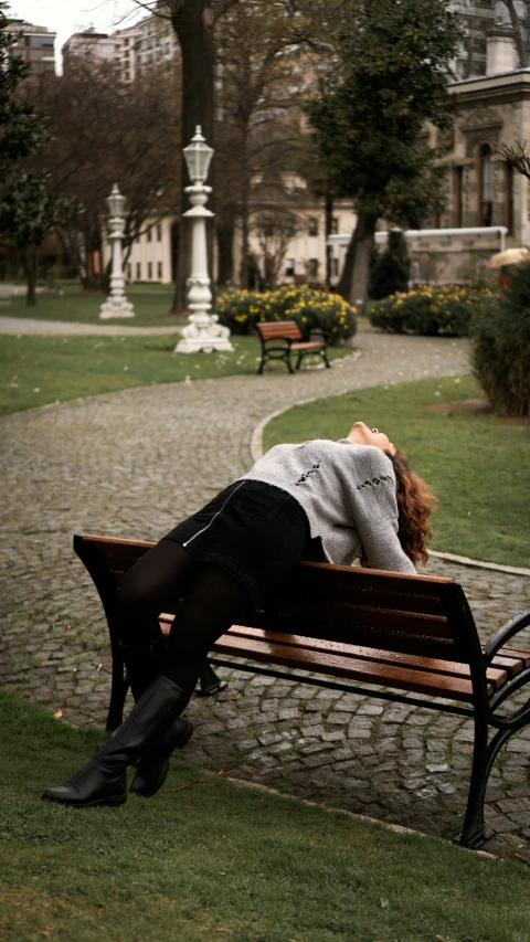 there is a woman laying down on the bench