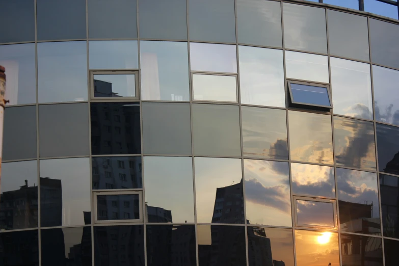 a building that is mirrored with windows at sunset