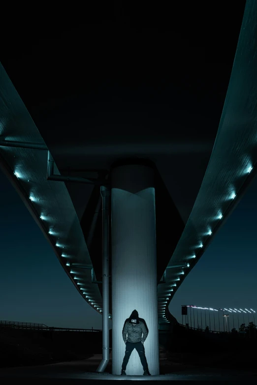 a man standing next to a large wall under a large overpass