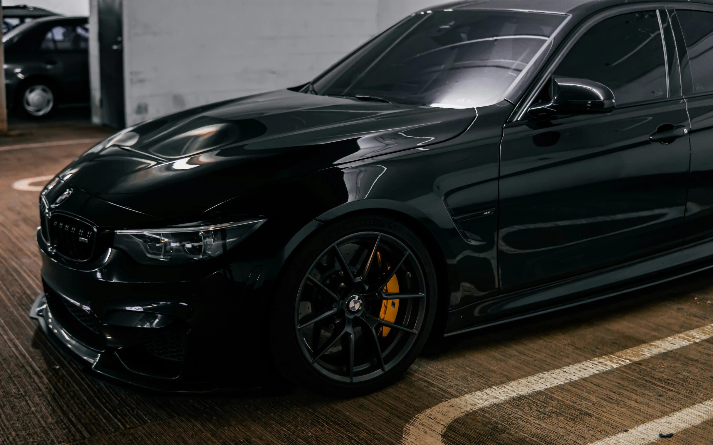 a black car in a garage with yellow tires