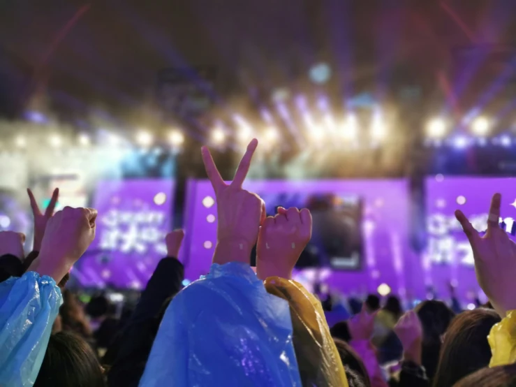 a crowd of people is raising their hands