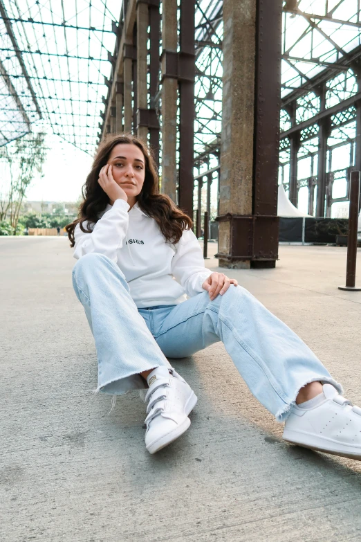 a woman in white shirt and jeans sitting on the ground