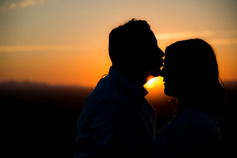 silhouettes of couple kissing against the sunset