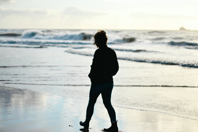 there is a woman standing at the edge of the beach