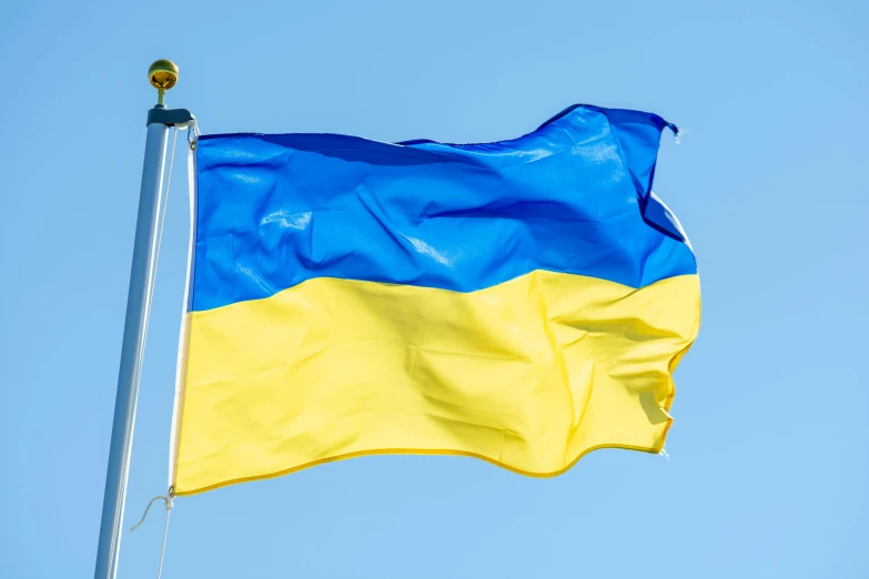 a flag with blue and yellow waves against a pale blue sky