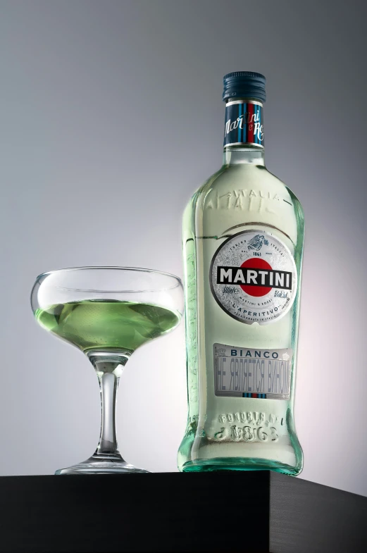 a glass and bottle of martini are next to it
