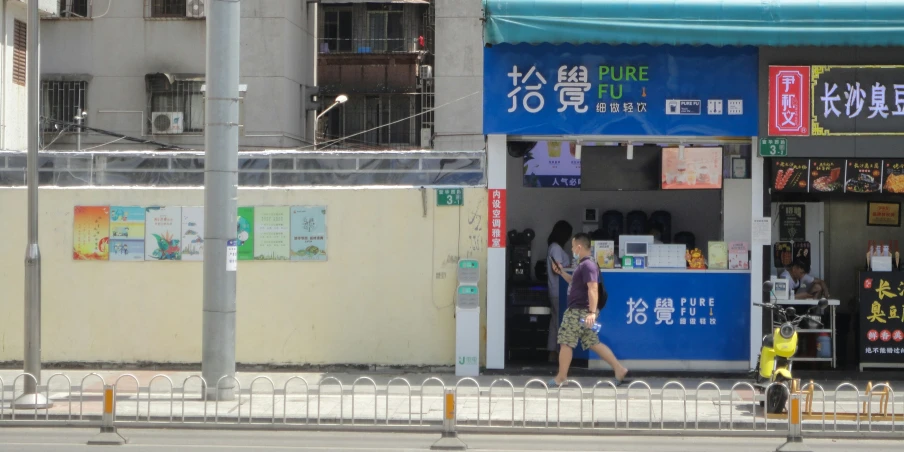 a woman walking past a blue sign and a store