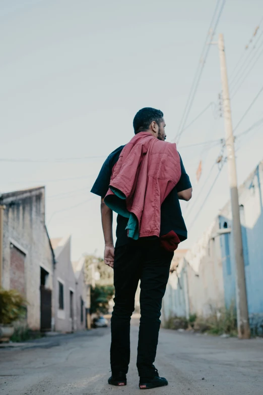 a man walking down the street carrying a pink blanket