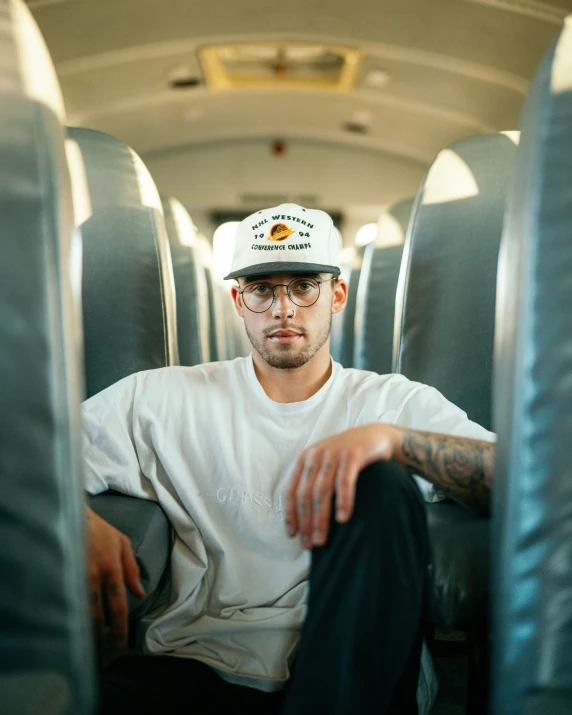 the young man is wearing a white hat while sitting on the bus