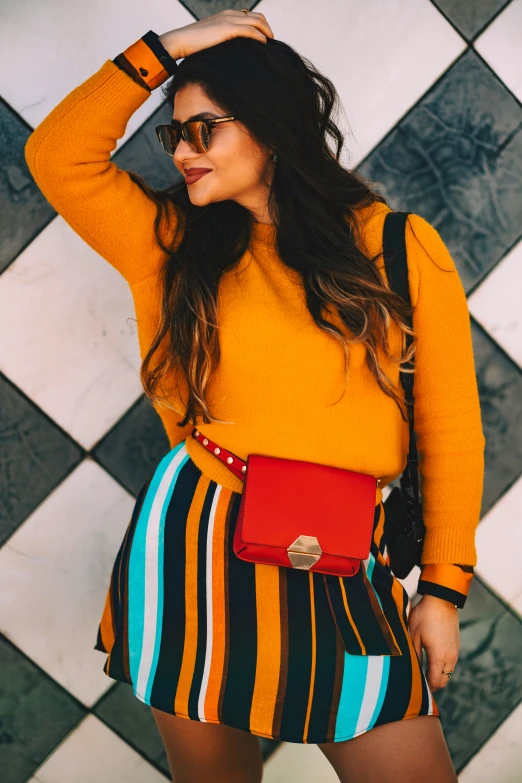 a girl in a yellow sweater stands with her hand on her hair