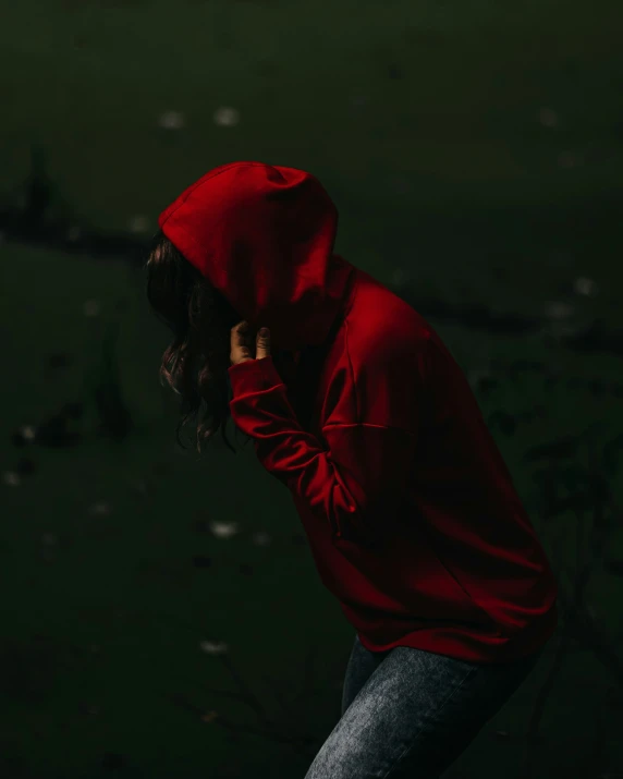 woman in red sweatshirt holding up phone while standing on grass