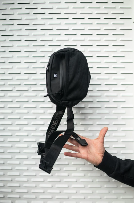 a hand holds out a shoulder bag on a wall