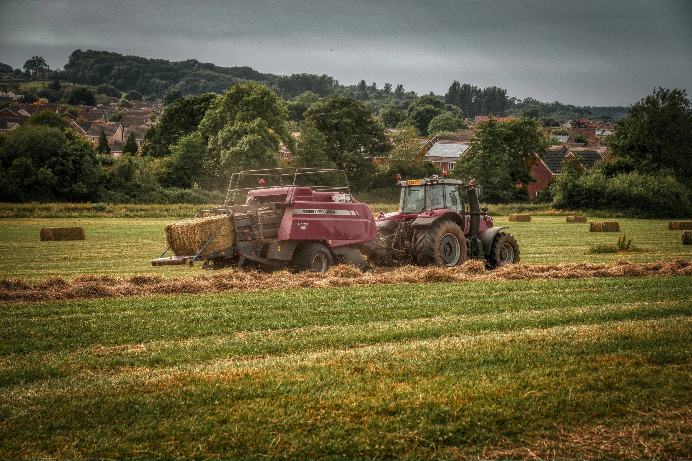 a tractor and trailer in a green field on a cloudy day