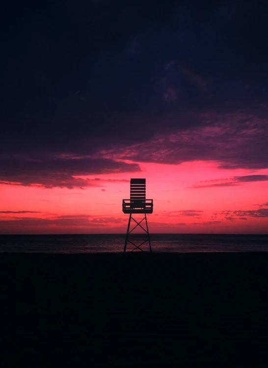 a lifeguard tower at sunset with the ocean behind it