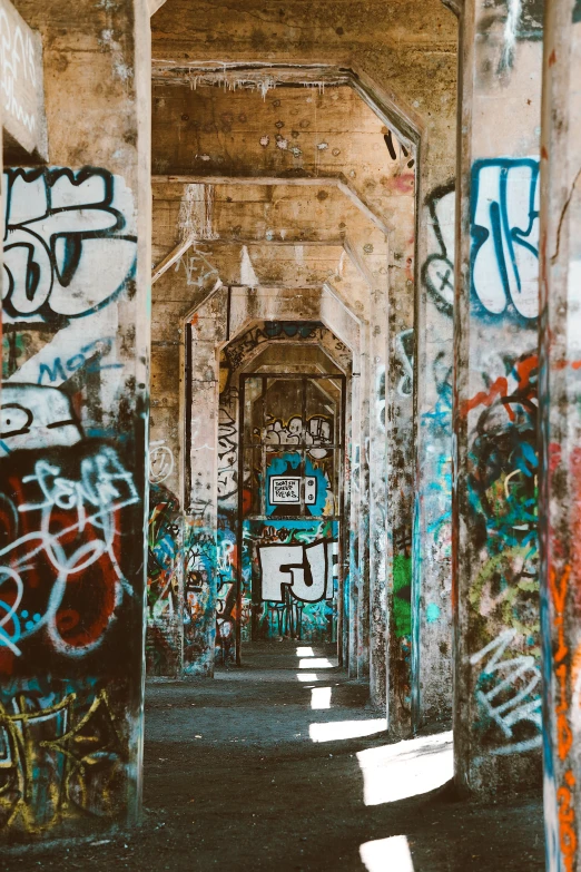 a long hallway covered in graffiti under a bridge