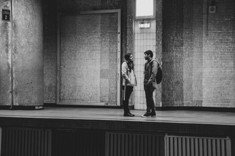 black and white pograph of two men talking in a hallway