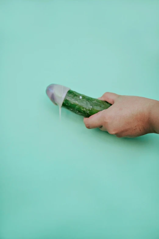 hand holding a pickle in a green table