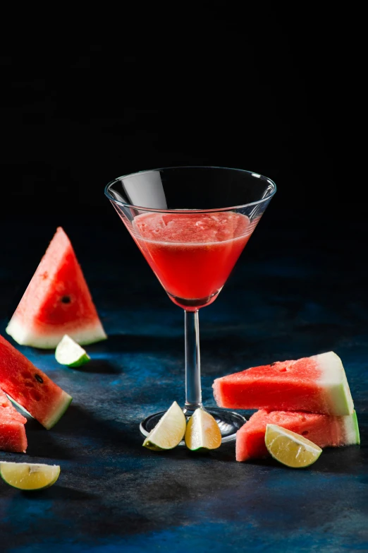 a watermelon martini in a coupe with a slice of lime and an apple