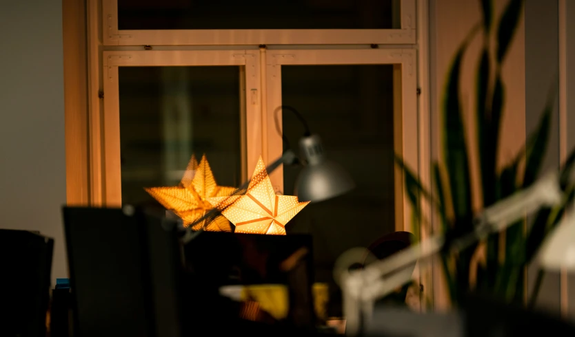 an upside down origami sun catcher in the sunlight next to some computer monitors