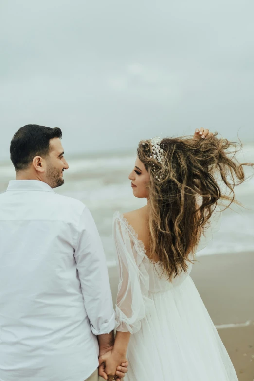 a man and woman walking on a beach holding hands