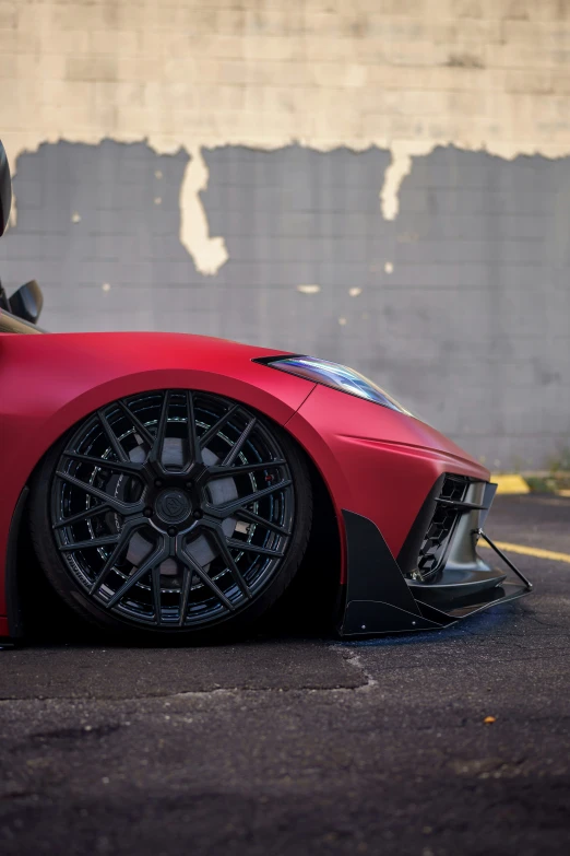 this sports car has black rims and is parked next to a brick wall