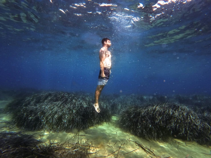 a man swimming in an open ocean next to rocks