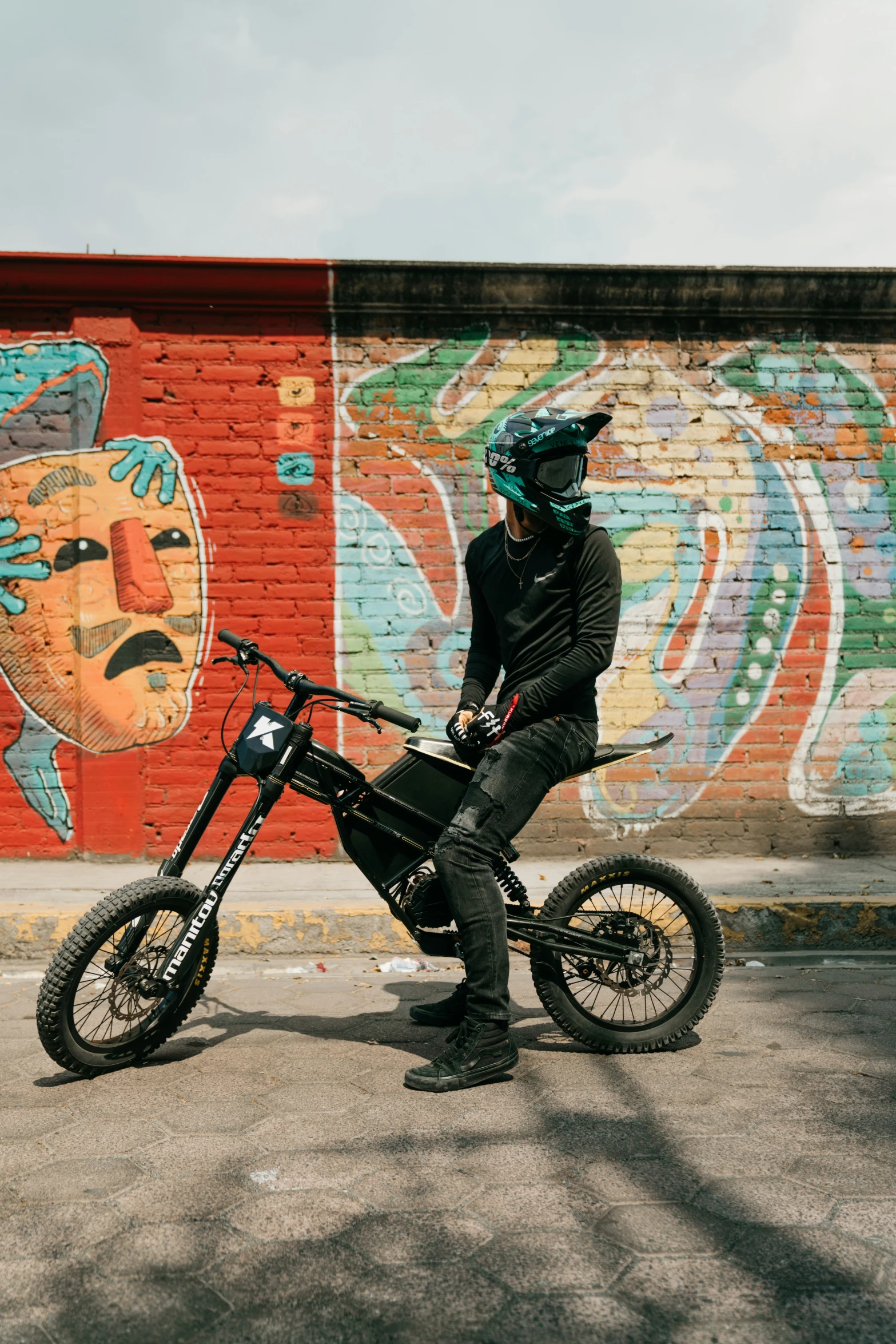 a man sitting on his bike with graffiti painted behind him