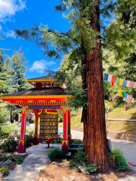 a pretty gazebo by a big tree and some flags