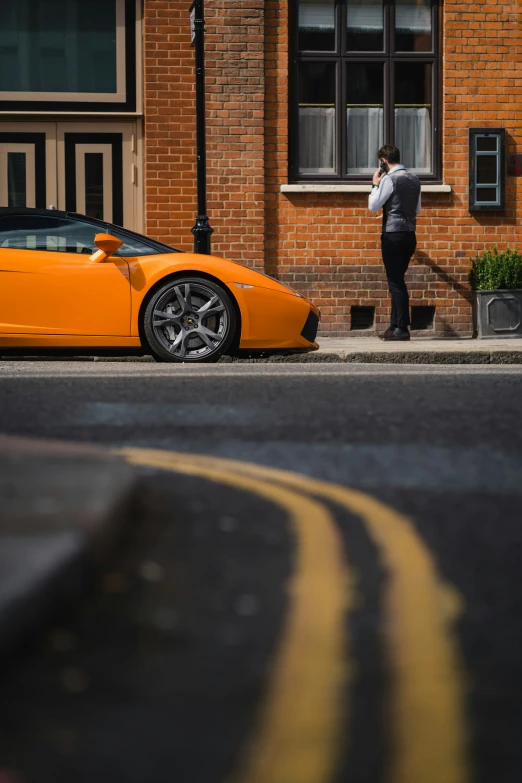 a woman standing outside a orange sports car