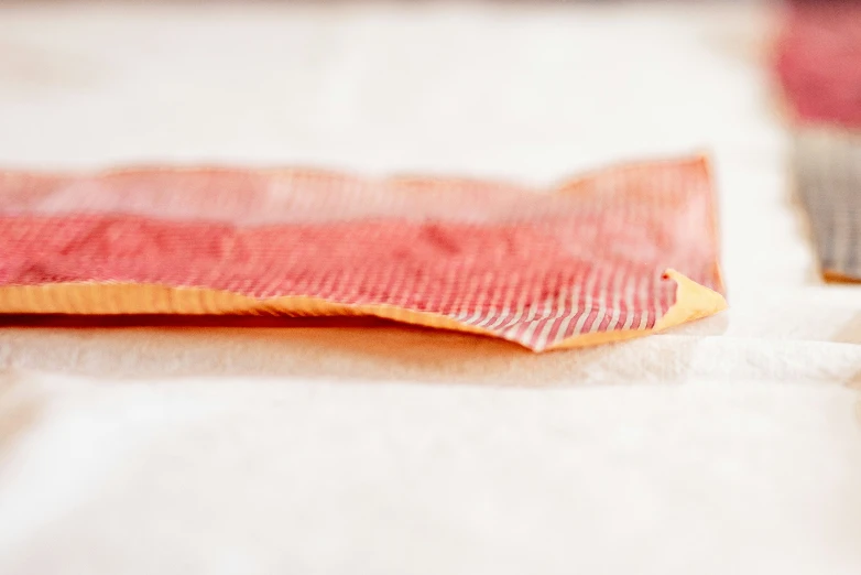 a piece of red and yellow paper on top of a white sheet