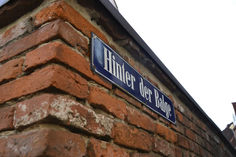 a blue street sign is mounted to the side of a brick wall