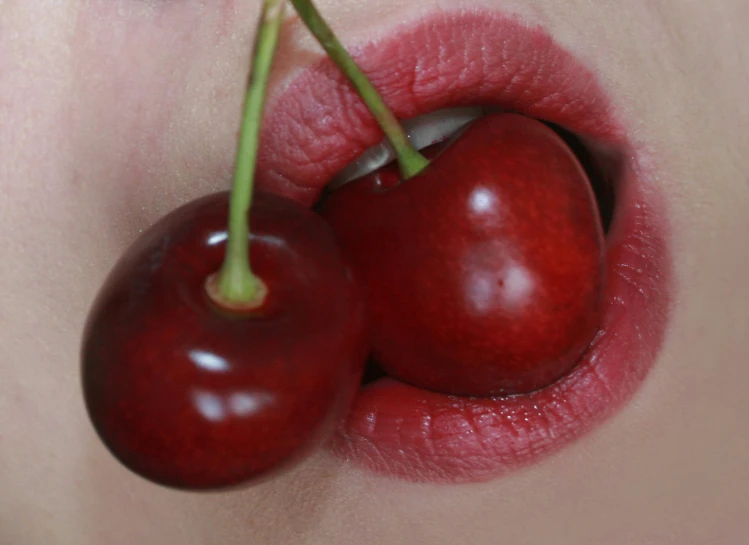 two cherries attached to the lip of a woman's body