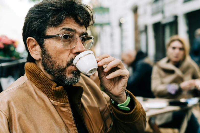 a man drinking out of a cup while sitting in a cafe