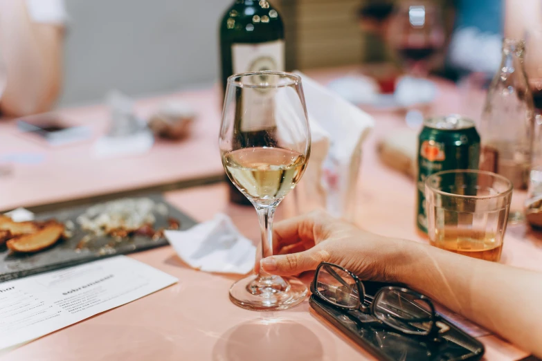 people's hands with wine glasses and plates of food on the table