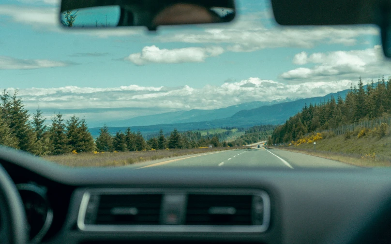 view out car windshield to road near mountainous area