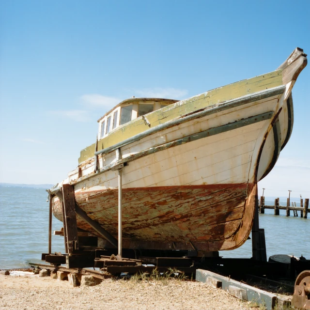 a boat sitting on the sand in a bay next to a dock