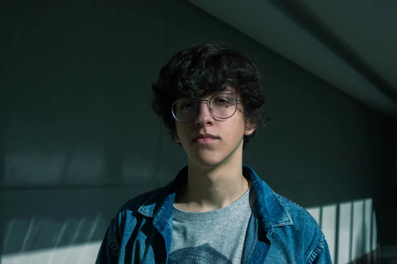 a boy with glasses standing in front of a wall