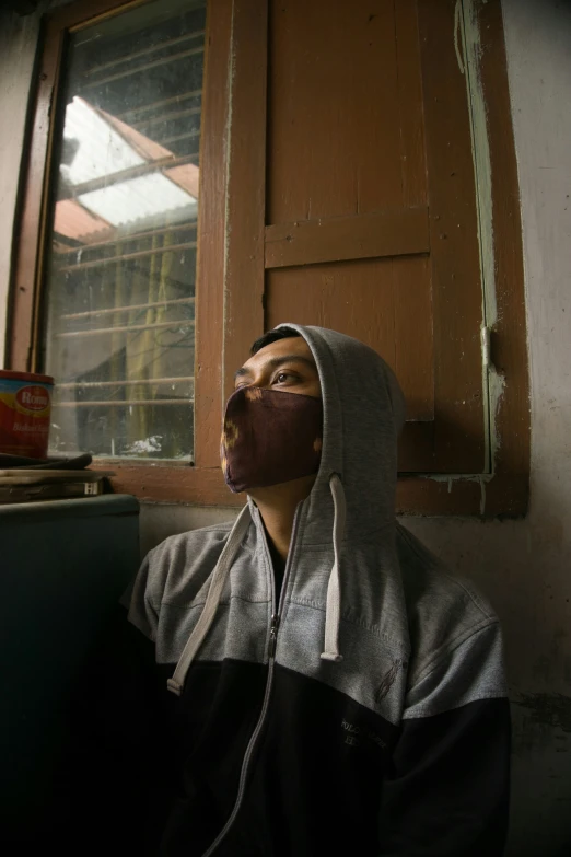 a man wearing a hood looks up into the sky