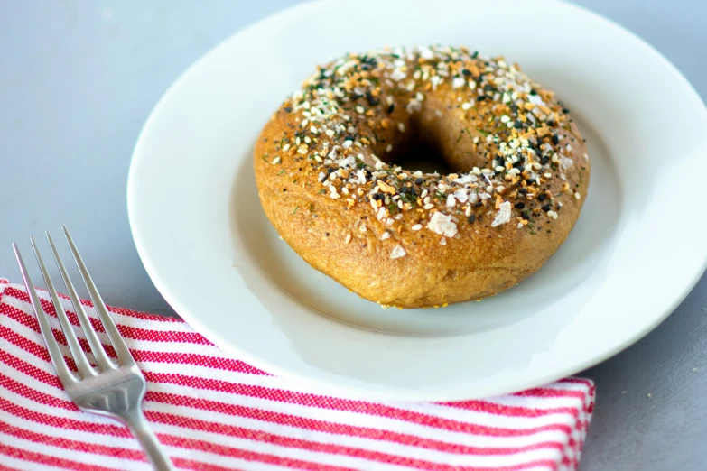 a donut sits on top of a plate next to a fork