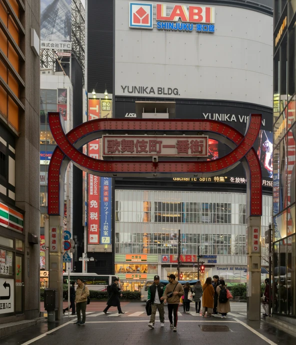 several people walk on a street underneath large arch